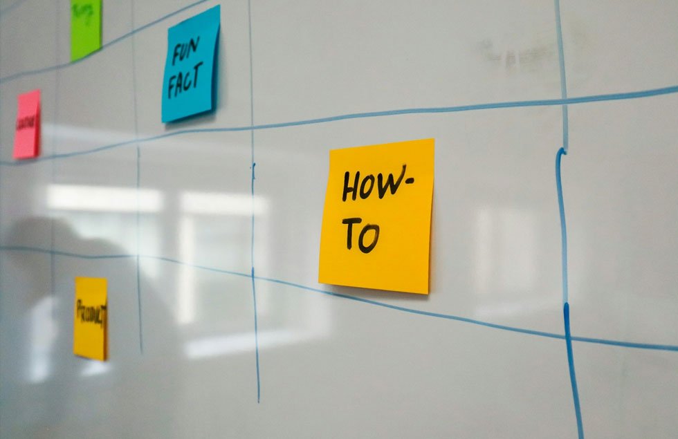 A how-to sticky note on a whiteboard planning grid
